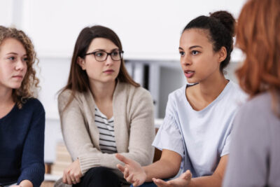 Women sitting and supporting each other during psychotherapy group meeting