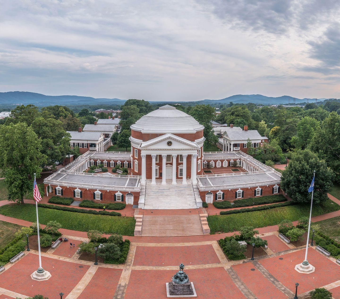 Arial-view-of-a-university-campus-featuring-a-neoclassical-rotunda-surrounded-by-lush-greenery-and-mountains-in-the-background