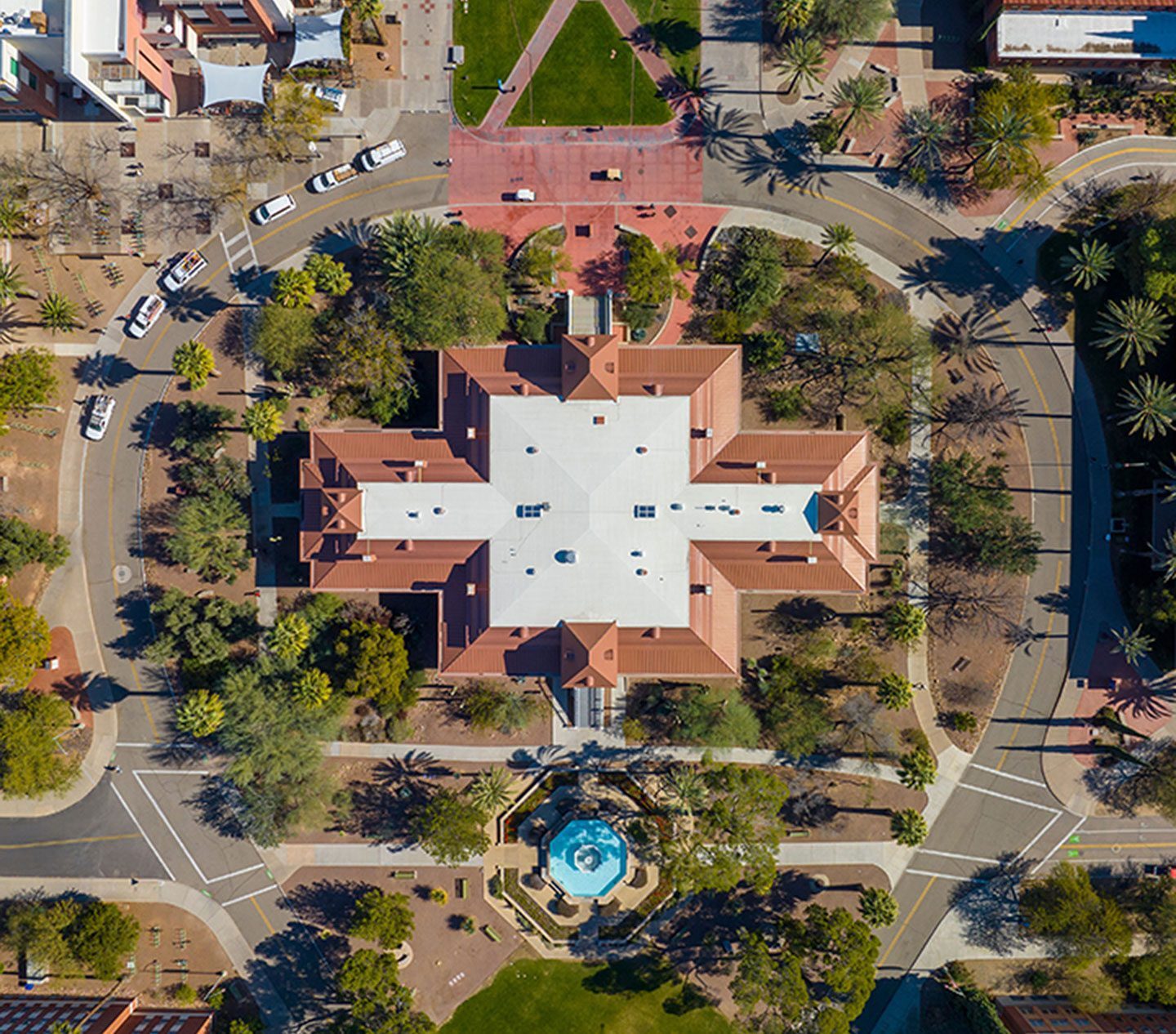 Top-down-view-of-a-university-campus-building-with-a-central-fountain-surrounded-by-trees-and-palm-lined-walkways