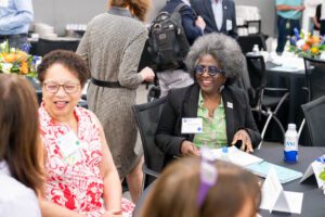 Woman smiling with group at table during the 2024 Presidential Experience Lab